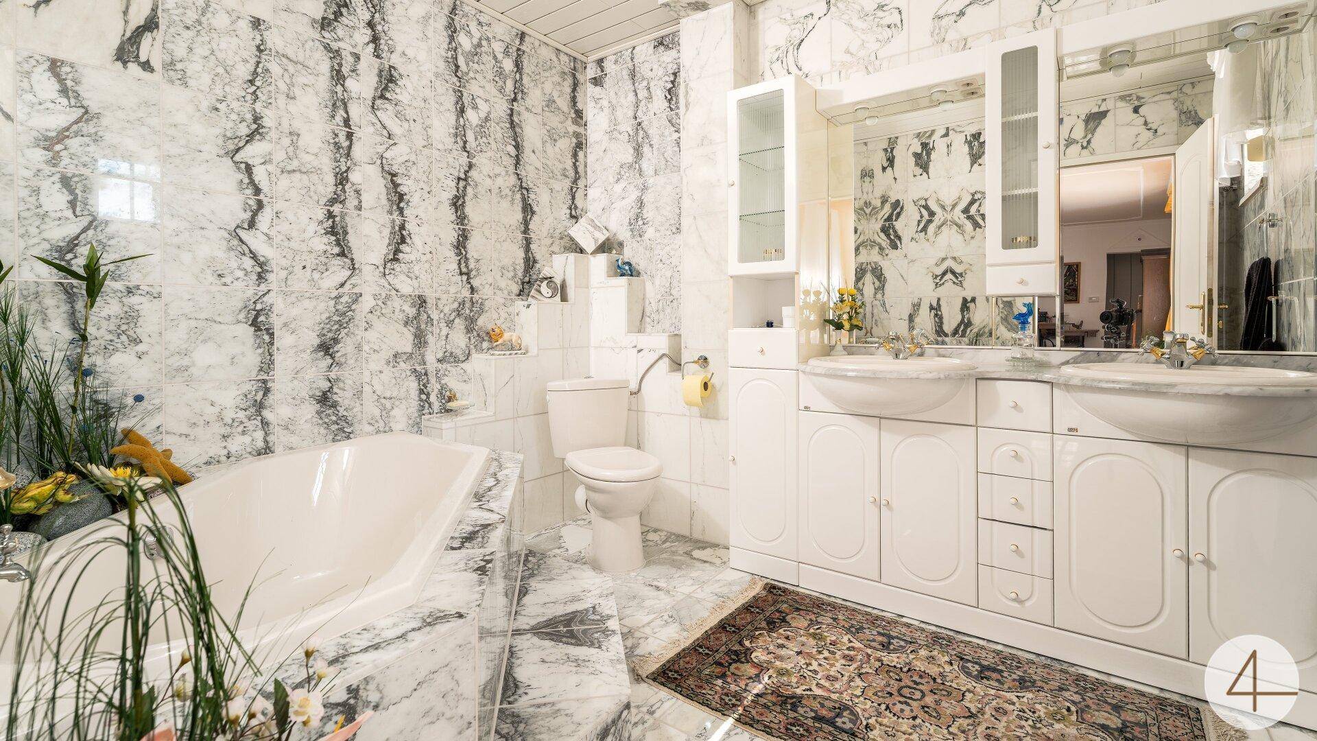 Geräumiges Badezimmer mit Marmorfliesen, Doppelwaschbecken und einer Badewanne in klassischem Stil.