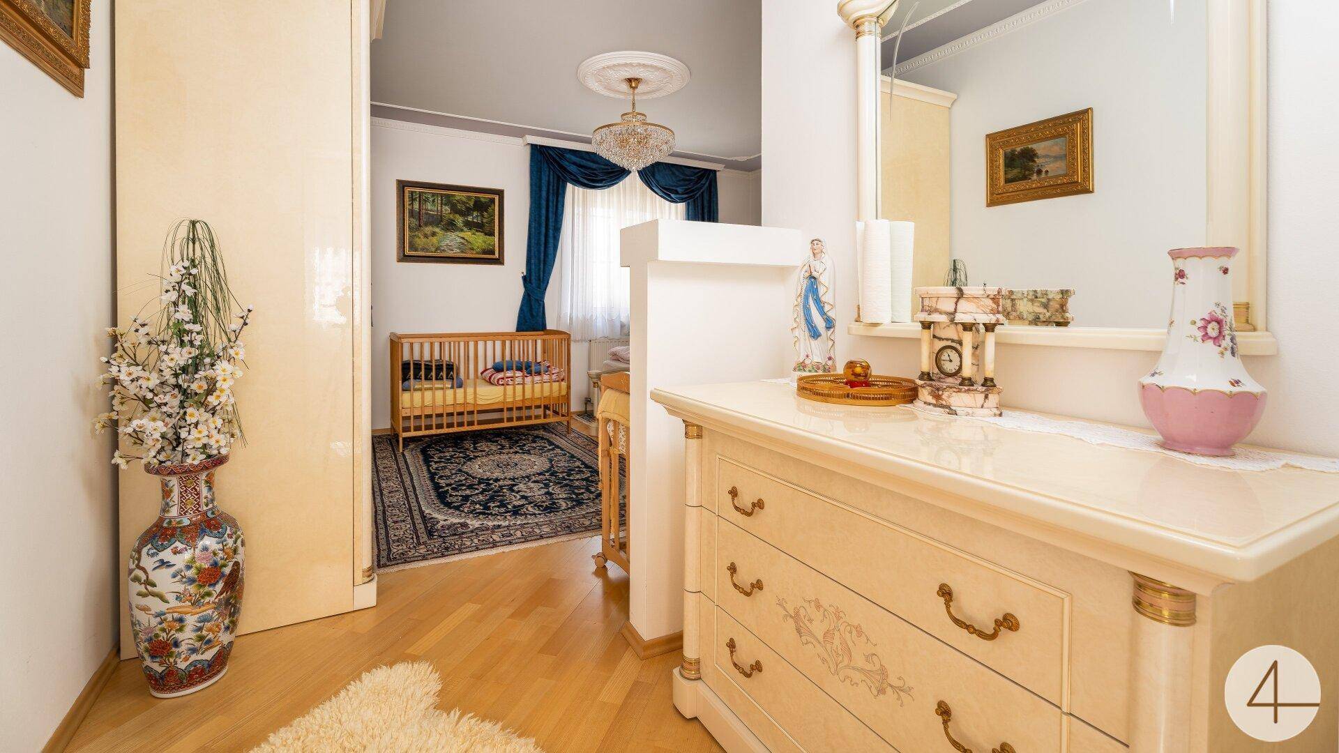 Elegante Kommode mit Spiegel in einem Flurbereich, der zu einem Kinderzimmer führt.