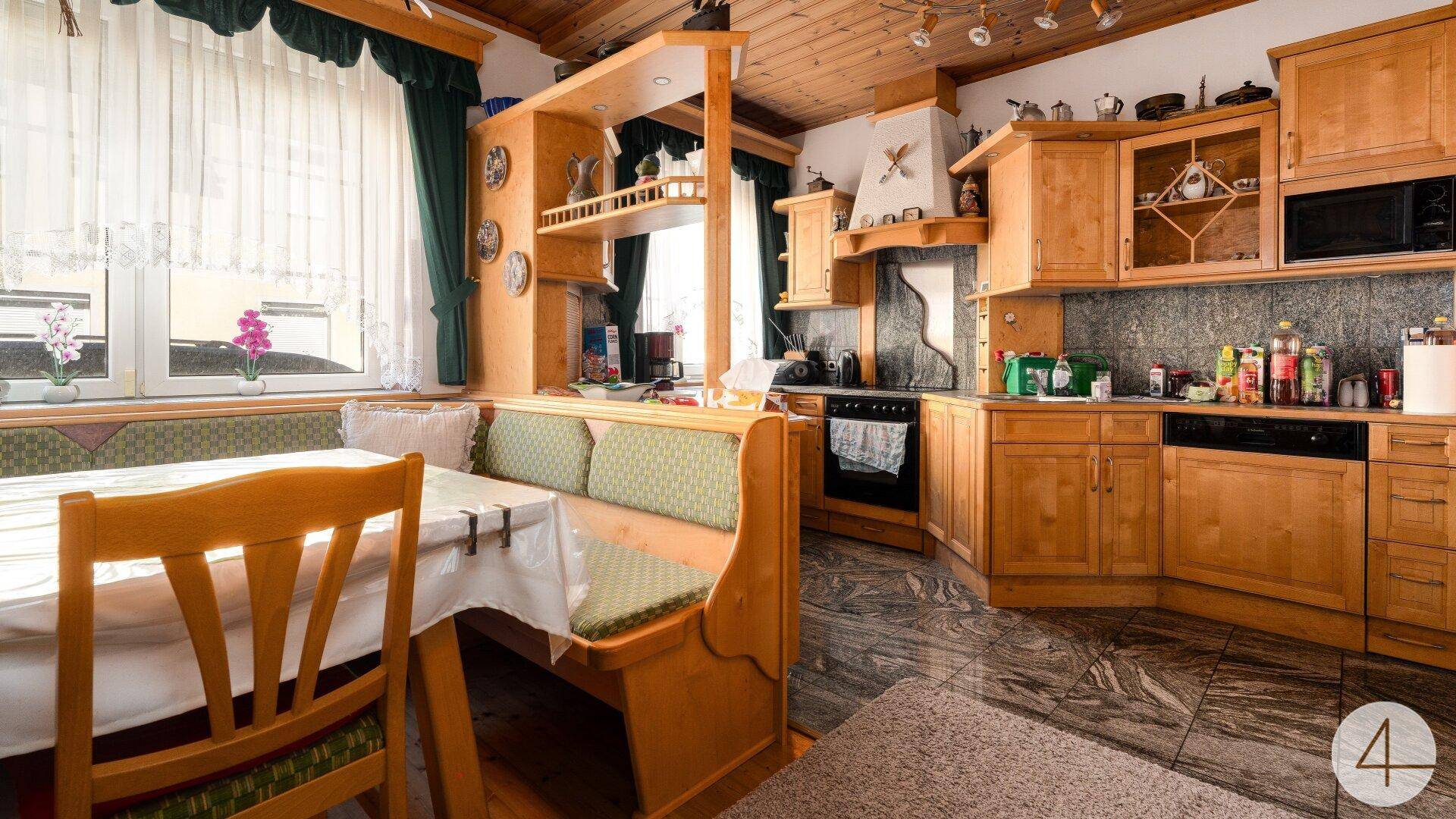 Rustikale Küche mit Holzmöbeln, integrierter Essecke und Blick nach draußen durch das Fenster.