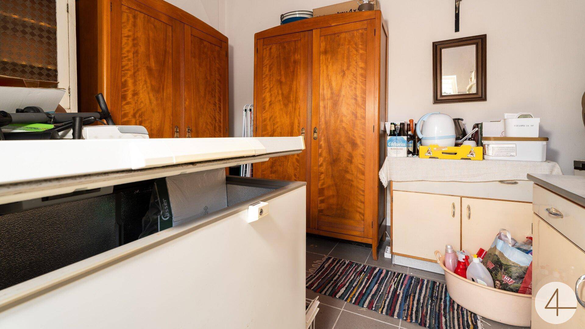 Praktischer Hauswirtschaftsraum mit großem Gefrierschrank, Holzschränken und Stauraum.