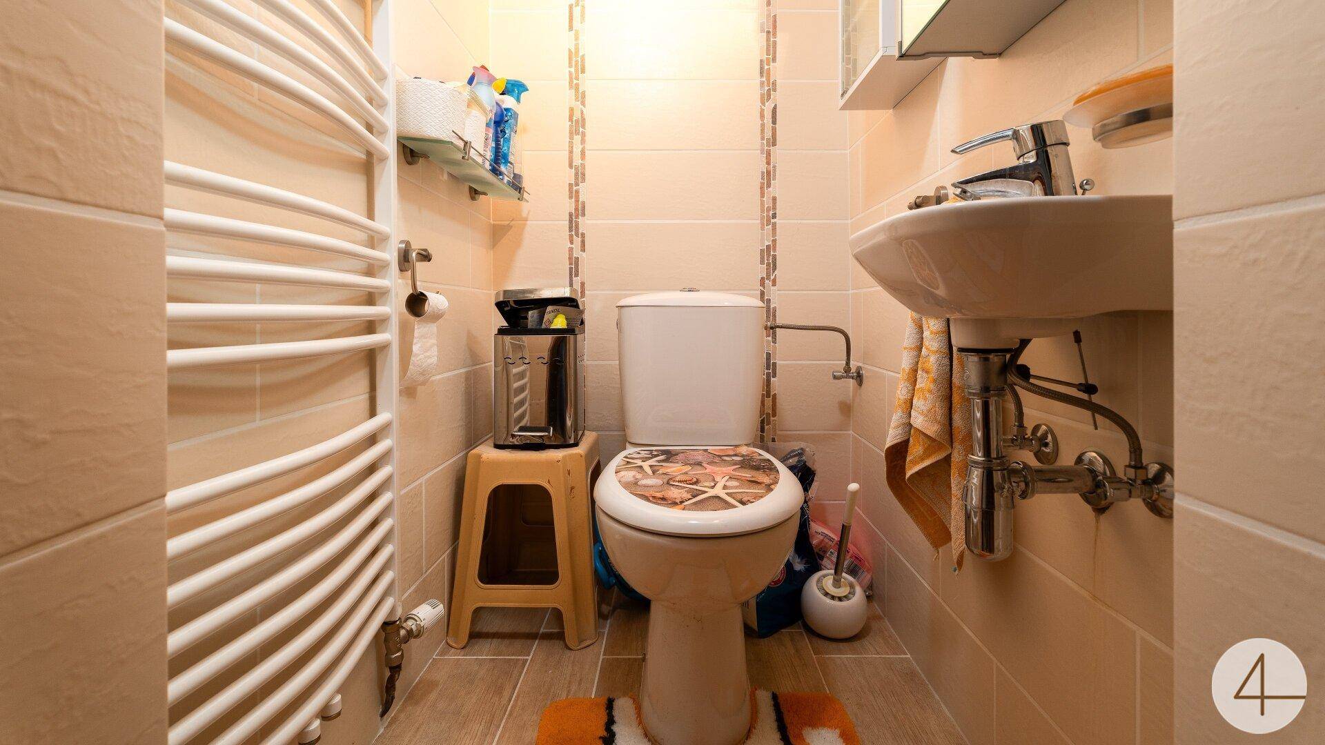 Kleines Gäste-WC mit Waschbecken, Toilette und einem beheizten Handtuchhalter.