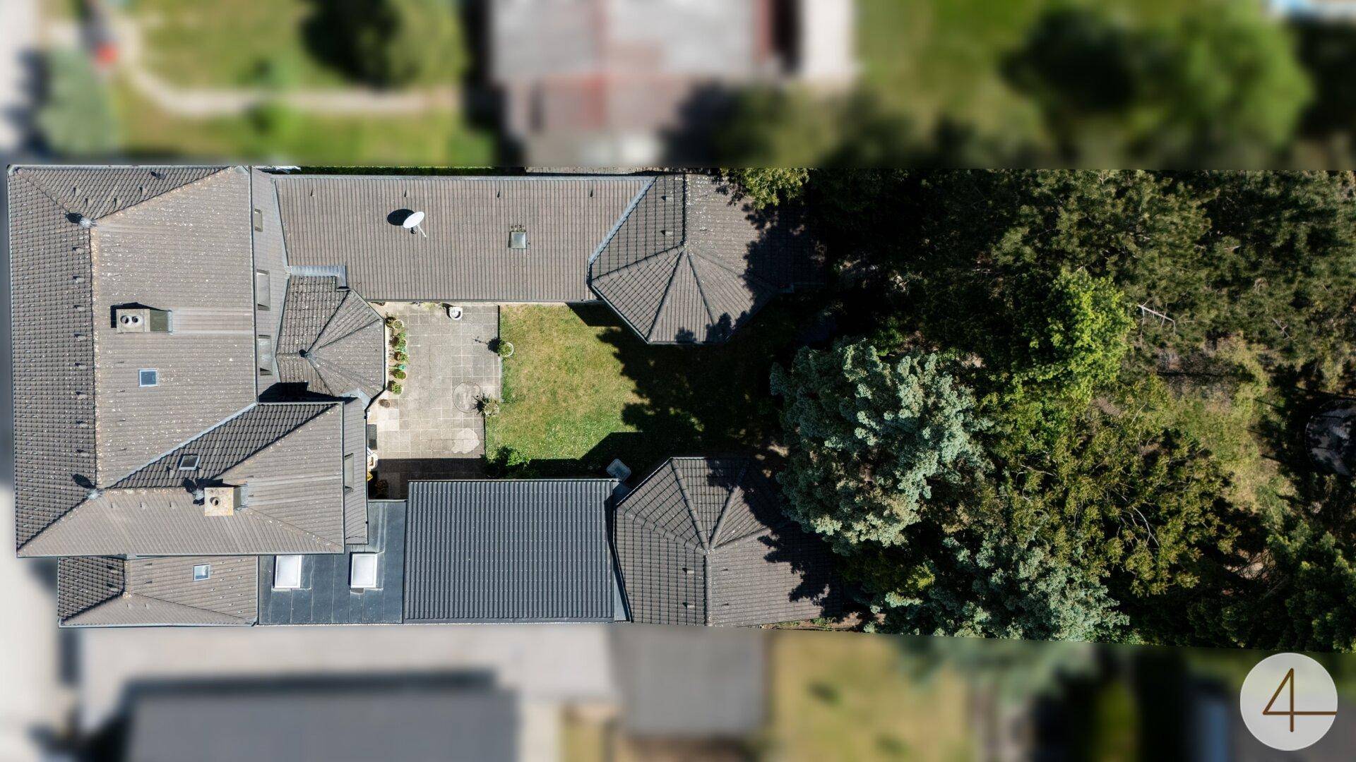 Vogelperspektive des Anwesens mit Hauptgebäude, Nebengebäuden und einem grünen Gartenbereich.