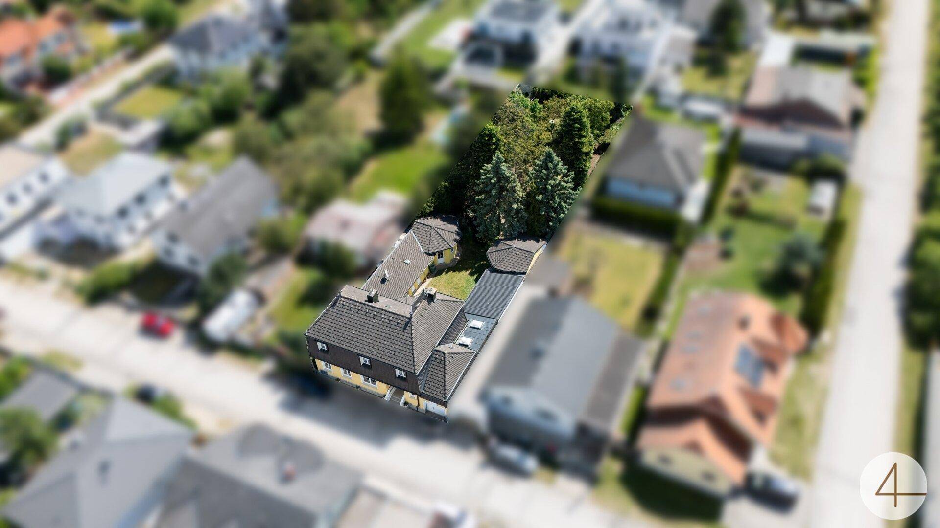Schrägansicht des Anwesens aus der Luft, eingebettet in eine Wohnsiedlung mit viel Grün.