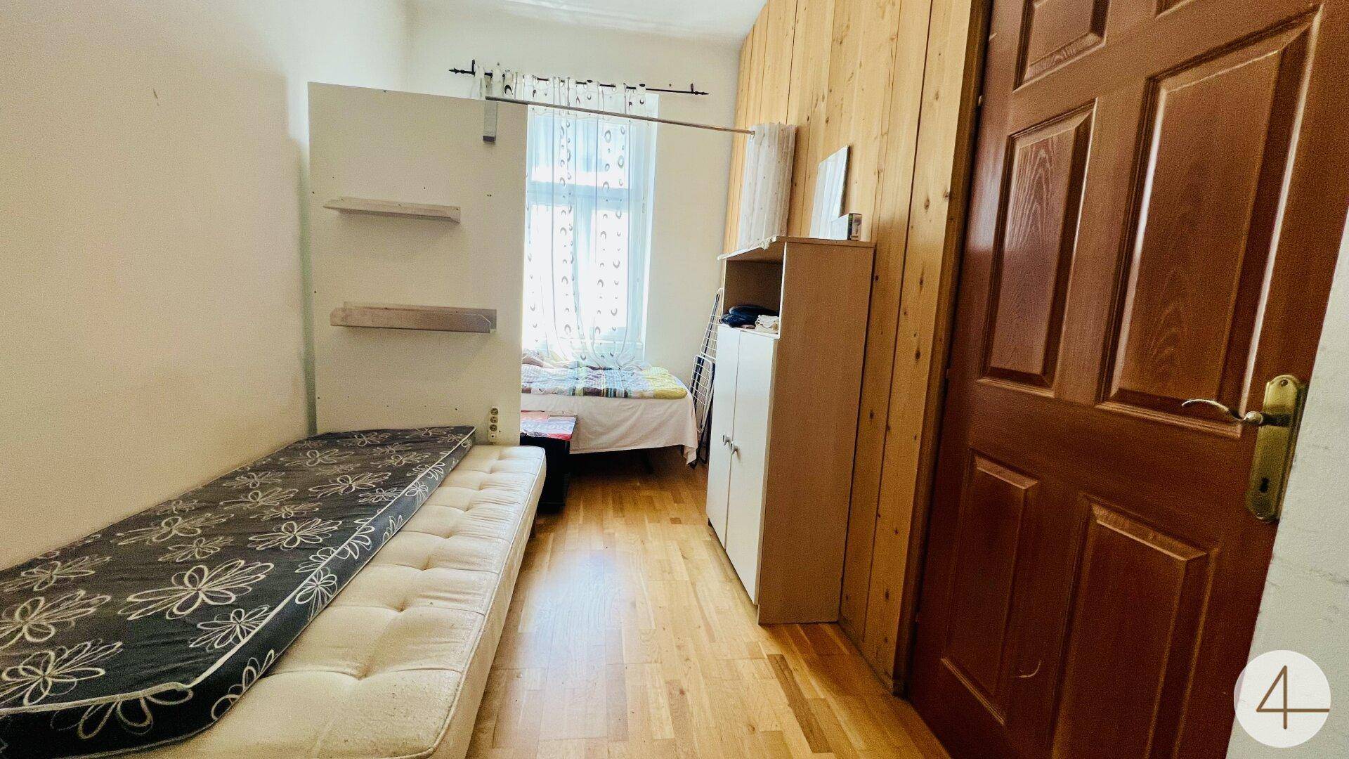 Schmales Schlafzimmer mit zwei Einzelbetten, Holzwandverkleidung und einem Fenster mit Vorhängen.