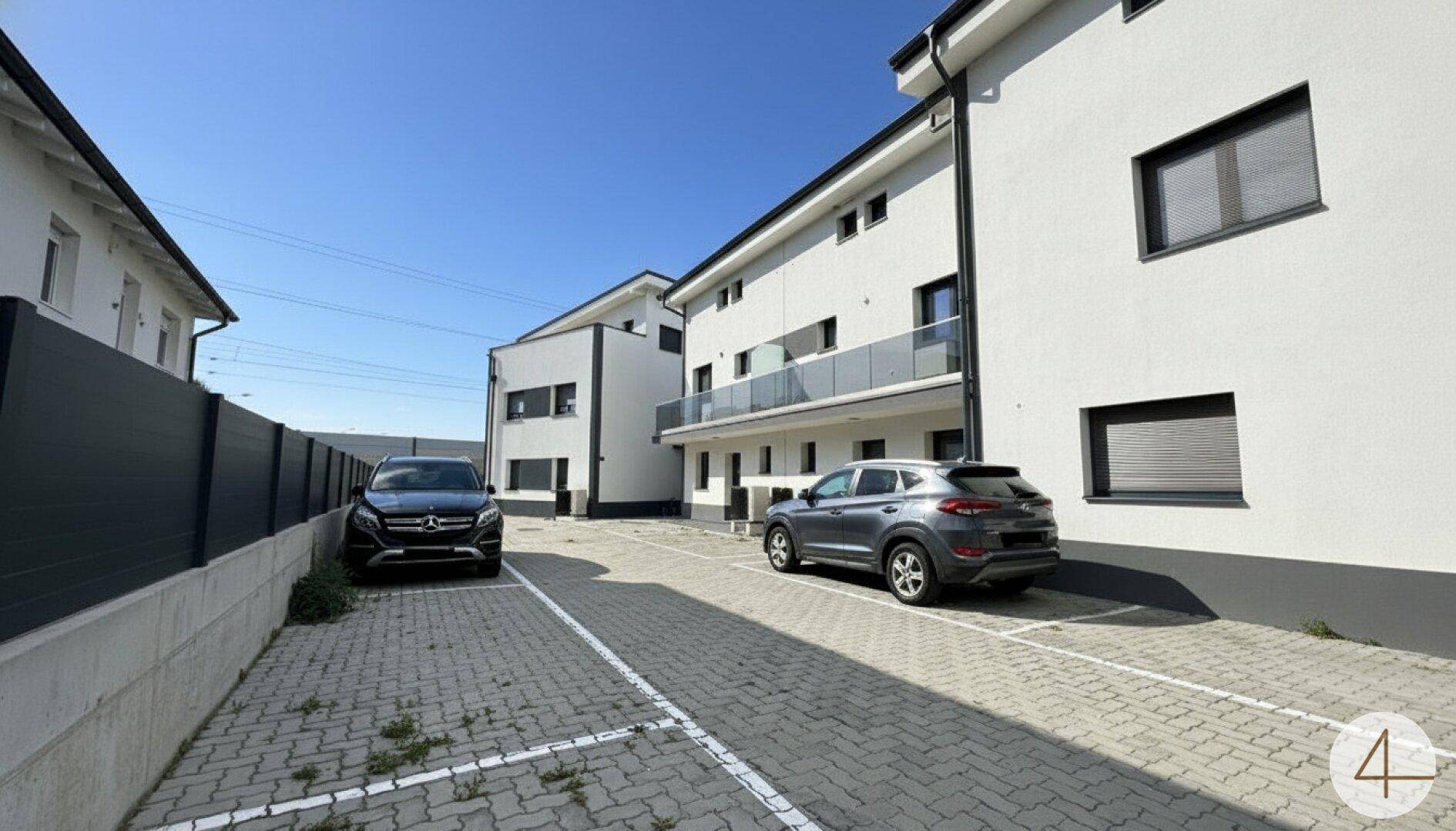 Außenansicht eines modernen Gebäudes mit gepflasterten Parkplätzen und klarem Himmel.
