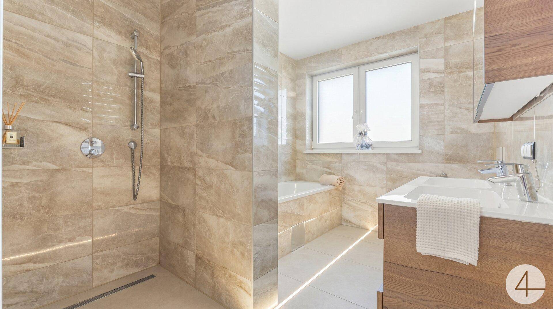 Modernes Badezimmer mit begehbarer Dusche, beigefarbenen Fliesen und indirekter Beleuchtung.