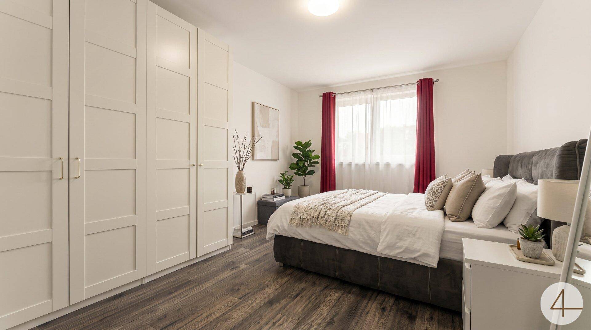 Helles Schlafzimmer mit Doppelbett, weißen Einbauschränken und Holzboden.