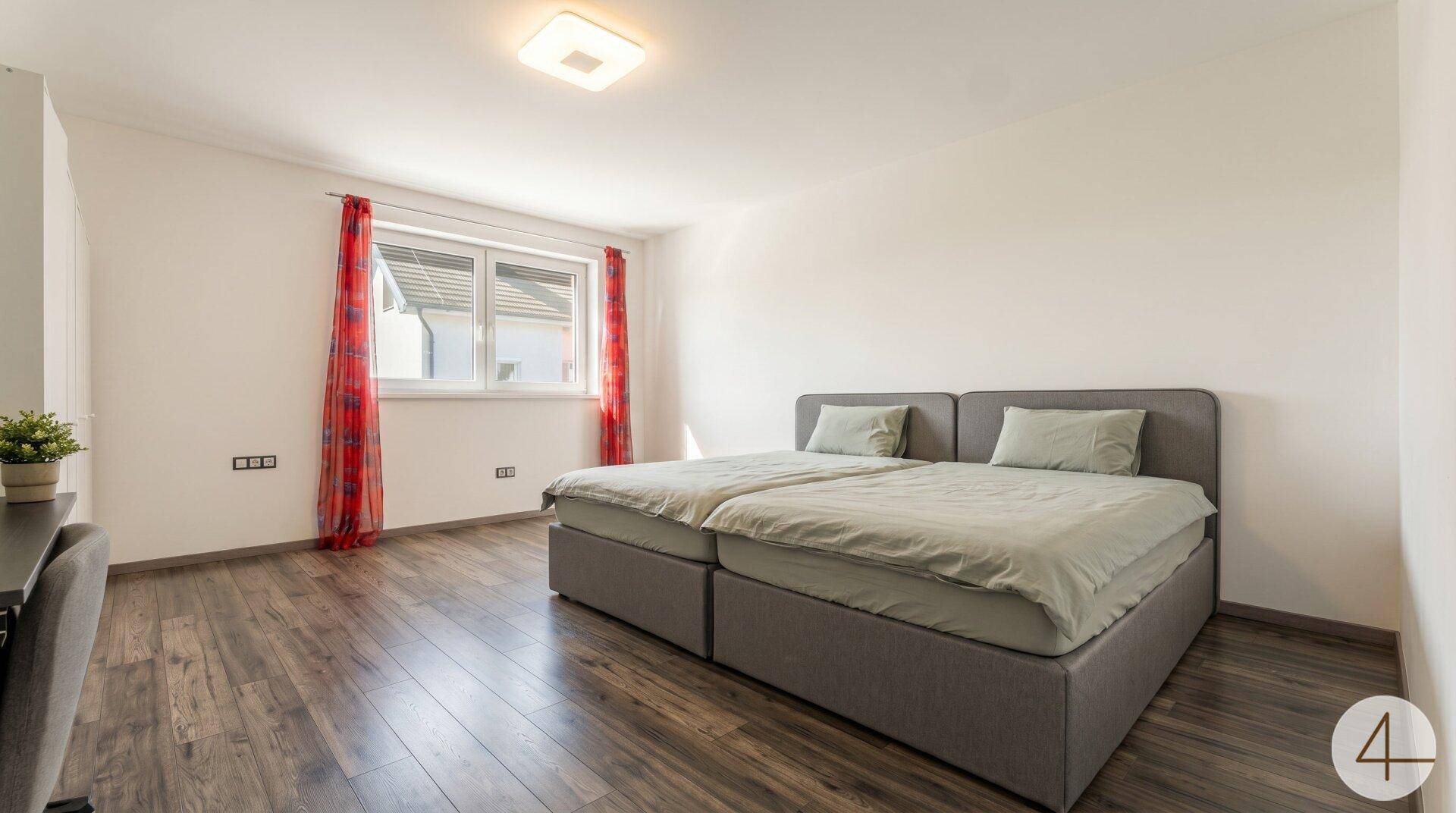 Geräumiges Schlafzimmer mit zwei Einzelbetten, Holzboden und Fenster mit Blick nach draußen.