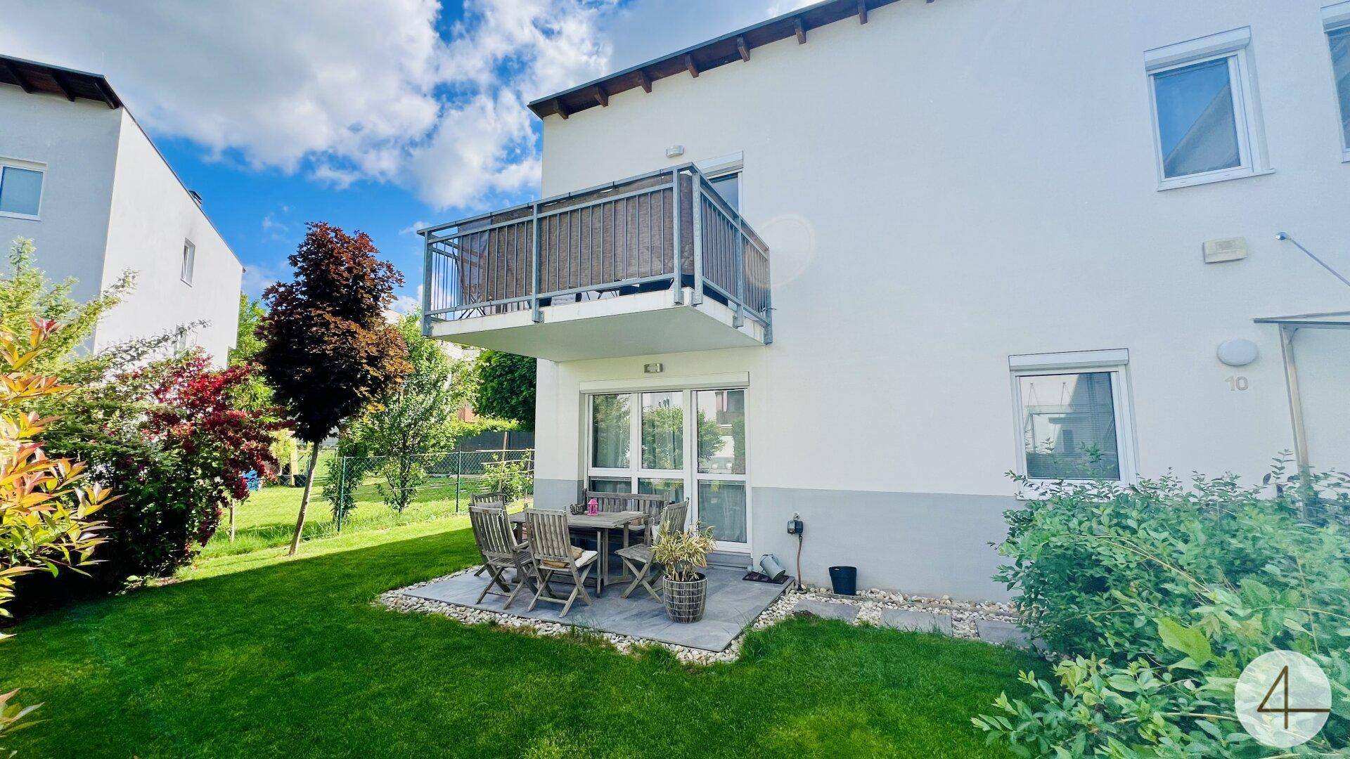 Gepflegter Gartenbereich mit kleiner Terrasse und Balkon im Obergeschoss des Hauses.