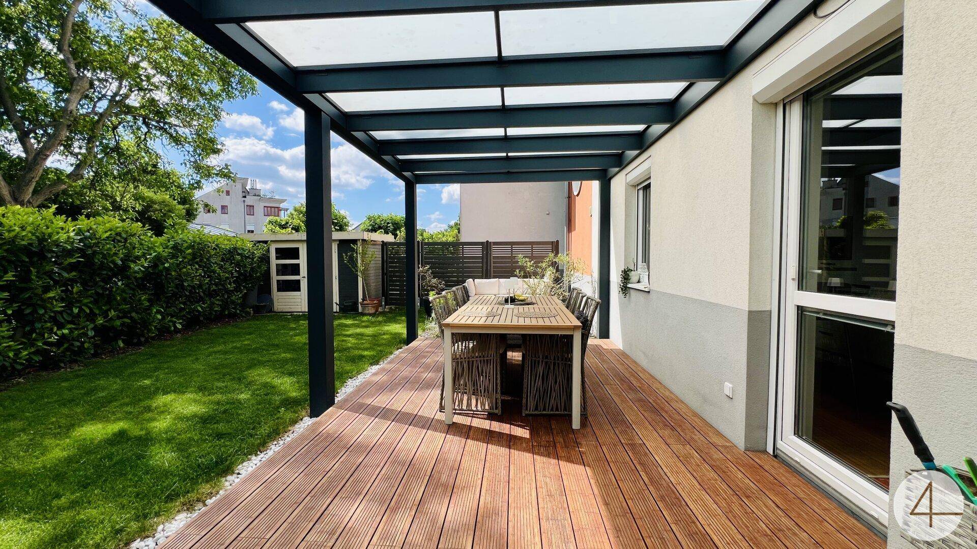 Geräumige Holzterrasse unter einer modernen Überdachung mit Blick auf den grünen Garten.