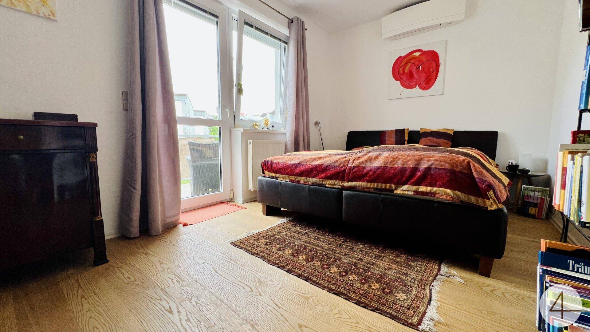 Gemütliches Schlafzimmer mit Holzboden, Klimaanlage und Zugang zum Balkon.