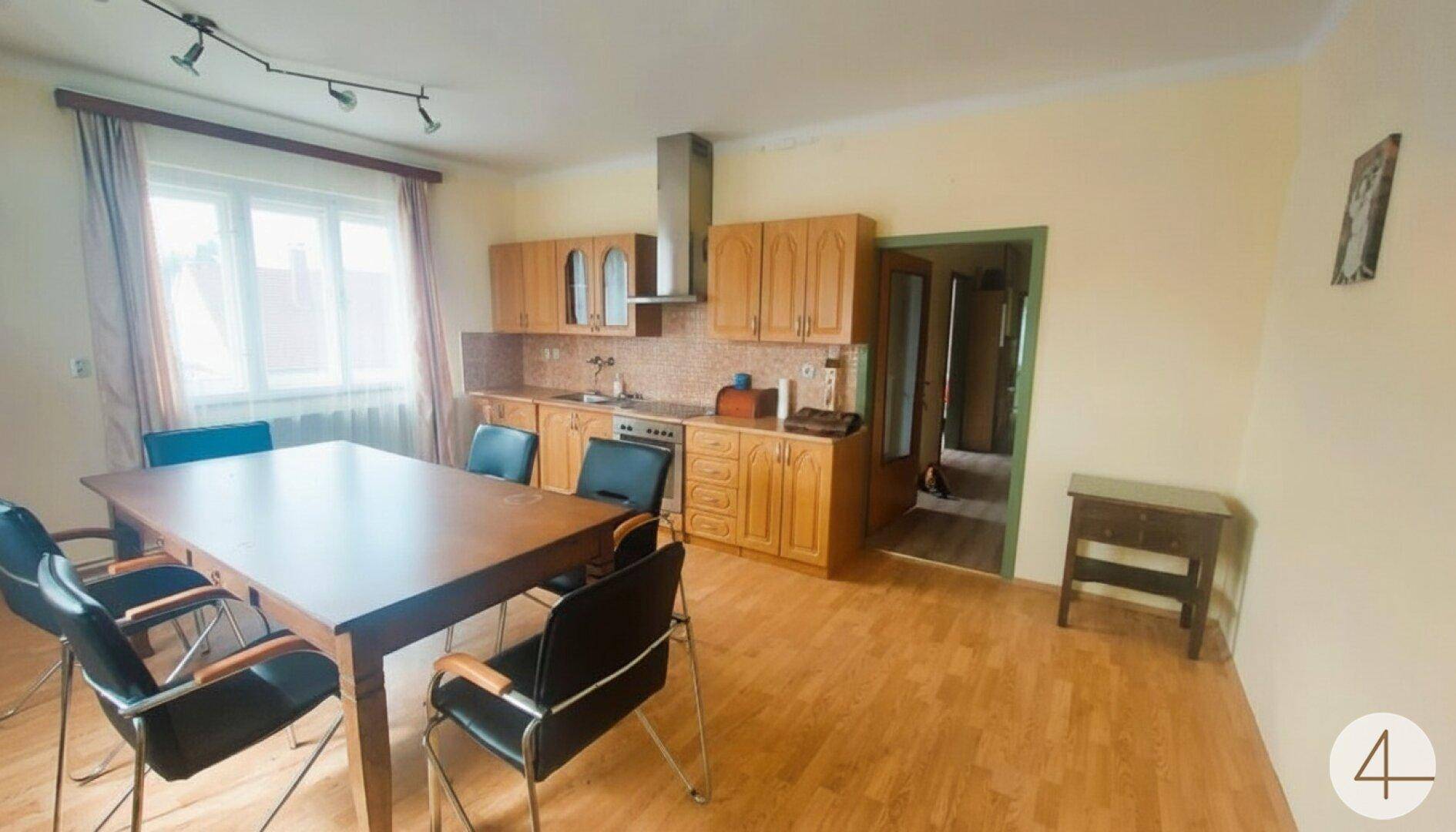 Küche mit Essbereich, Holzschränken, Laminatboden und Fenster, funktional eingerichtet.