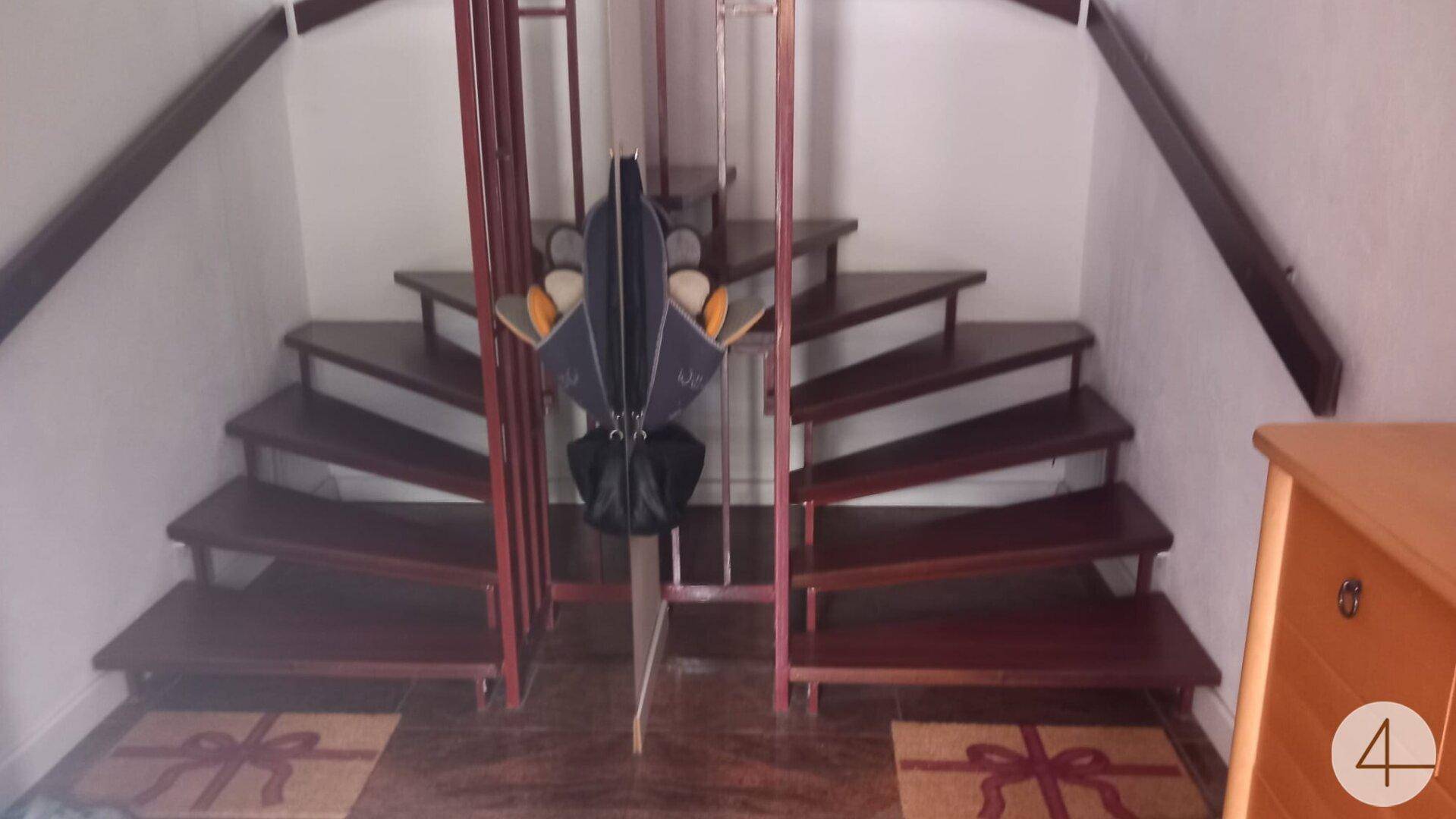 Holztreppe mit dunklen Stufen und Geländer in einem Eingangsbereich, der zu weiteren Etagen führt.