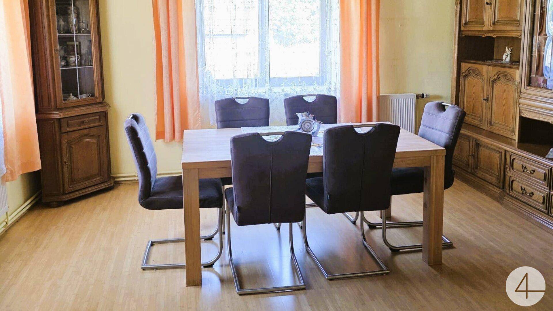 Gemütliches Esszimmer mit Holztisch, Stühlen und traditionellen Holzschränken.