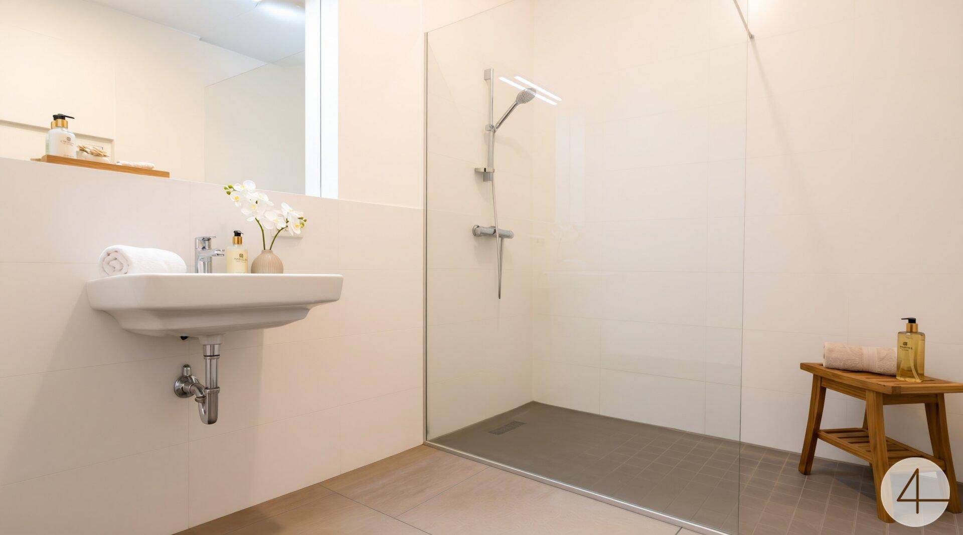 Modernes Badezimmer mit ebenerdiger Dusche und elegantem Waschbecken, minimalistisch und funktional gestaltet.