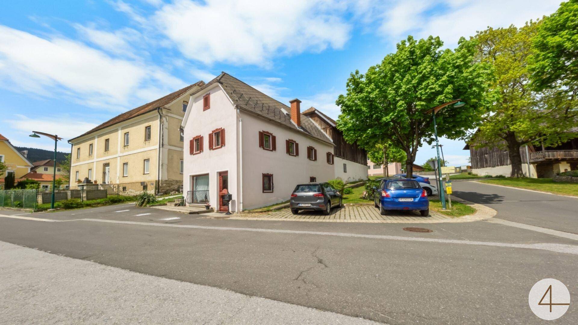 Ansicht des Gebäudes von der Straße mit parkenden Autos und umliegender Bebauung.
