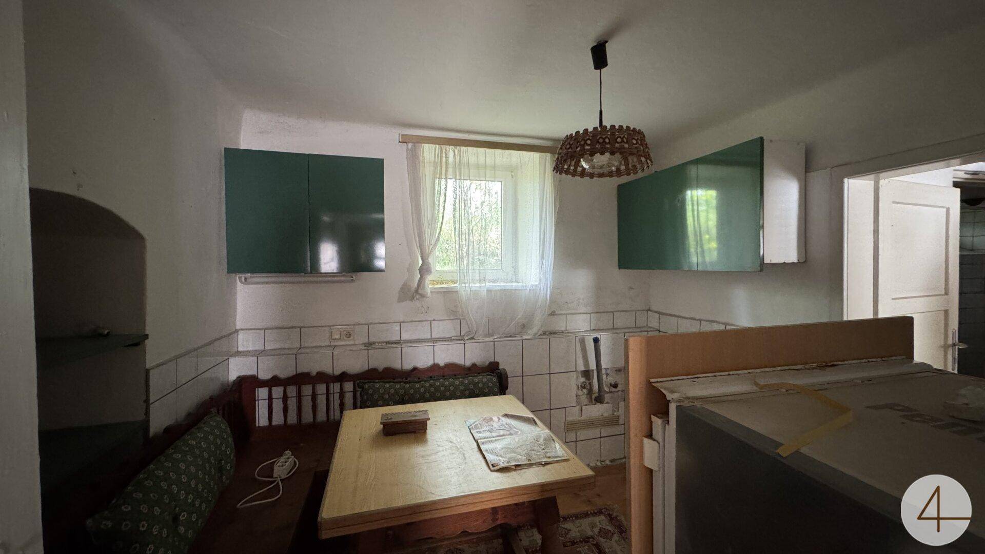 Rustikale Küche mit Holztisch, Sitzbank und grünen Hängeschränken.
