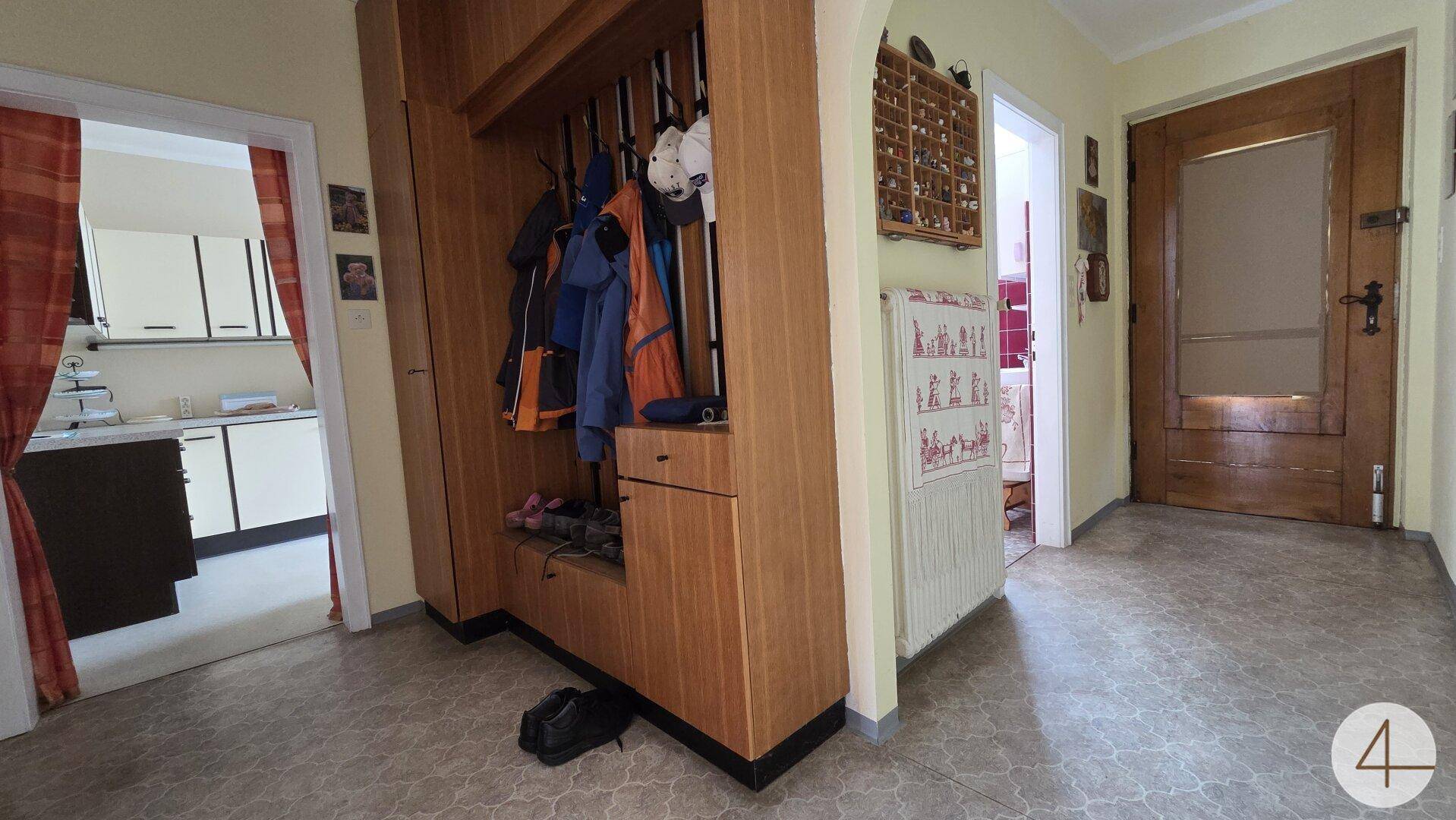 Eingangsbereich mit Garderobe aus Holz, Fliesenboden und Zugang zu weiteren Räumen des Hauses.