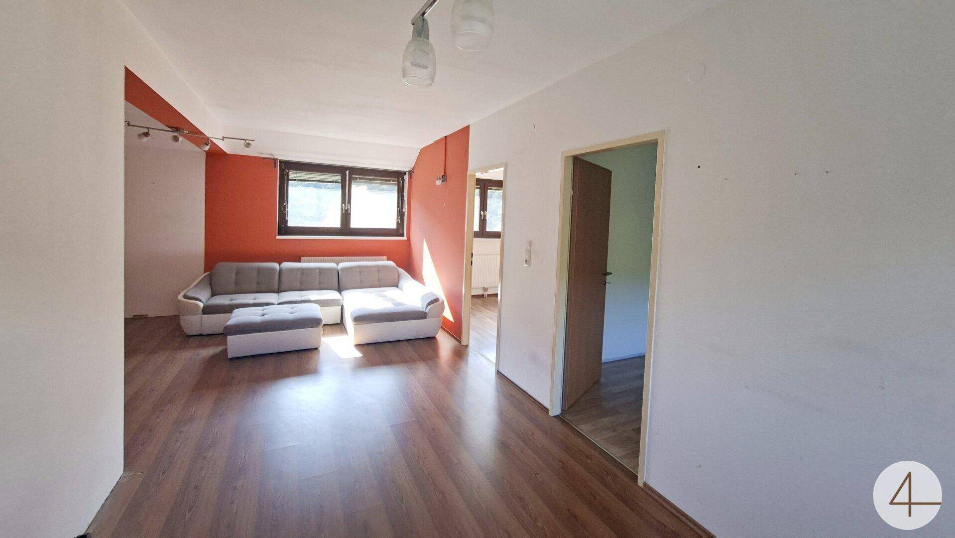 Geräumiges Wohnzimmer mit Laminatboden und viel Tageslicht, bereit zur individuellen Einrichtung.
