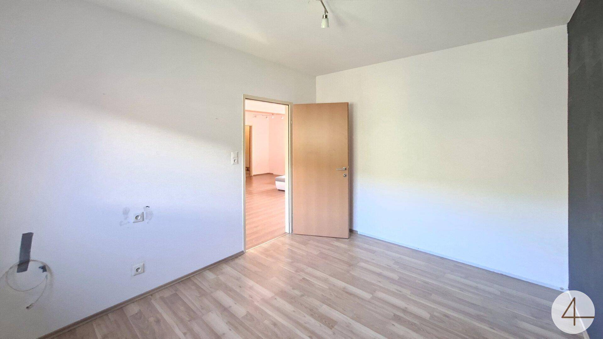 Schlafzimmer mit Laminatboden und weiß gestrichenen Wänden, bereit zur individuellen Gestaltung.