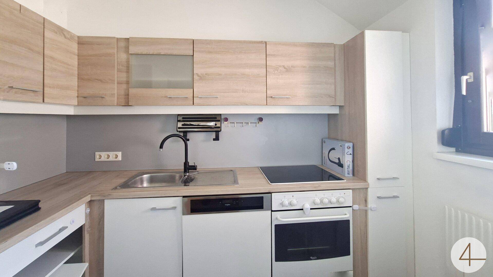 Funktionale Einbauküche mit hellen Holzfronten, Spülmaschine und Cerankochfeld.