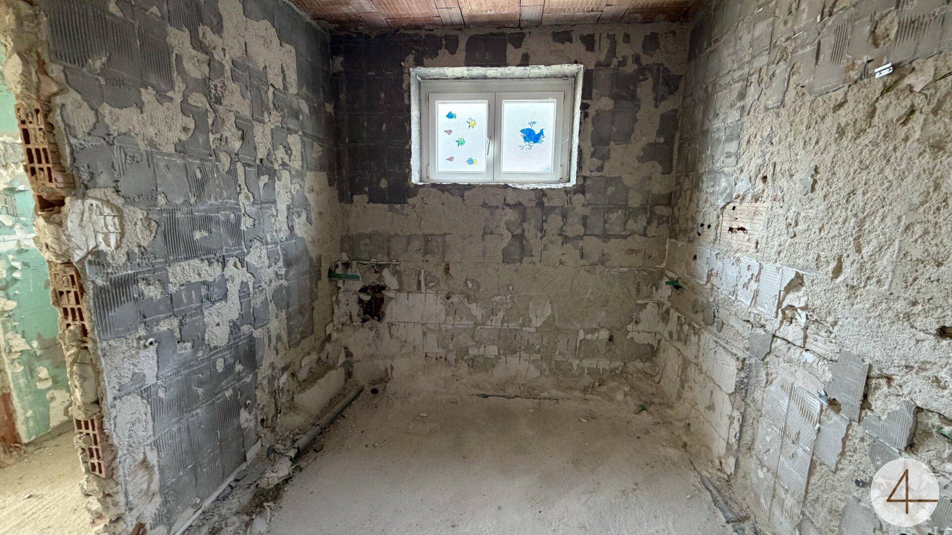 Weiteres Badezimmer in Renovierung mit freigelegten Wänden und einem Fenster.