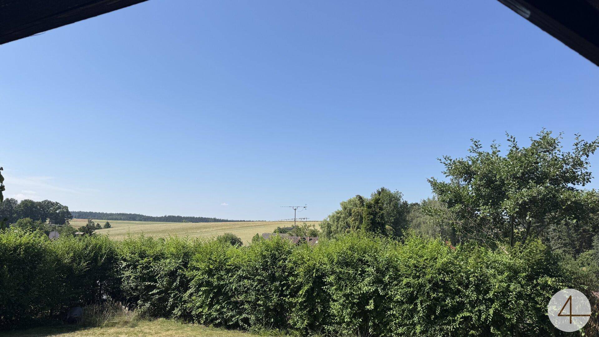Weitläufiger Blick über grüne Felder und die ländliche Umgebung unter einem strahlend blauen Himmel.