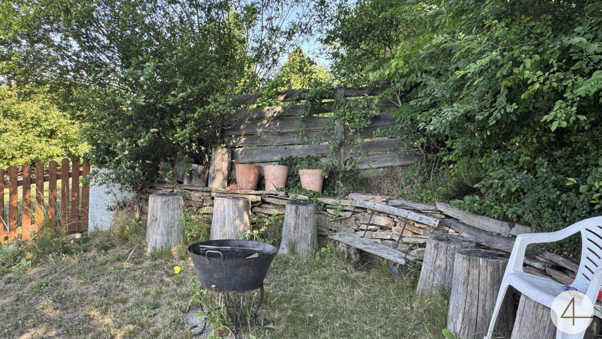 Gemütlicher Gartenbereich mit Baumstumpf-Sitzgelegenheiten, Feuerstelle und rustikaler Holzeinfassung.