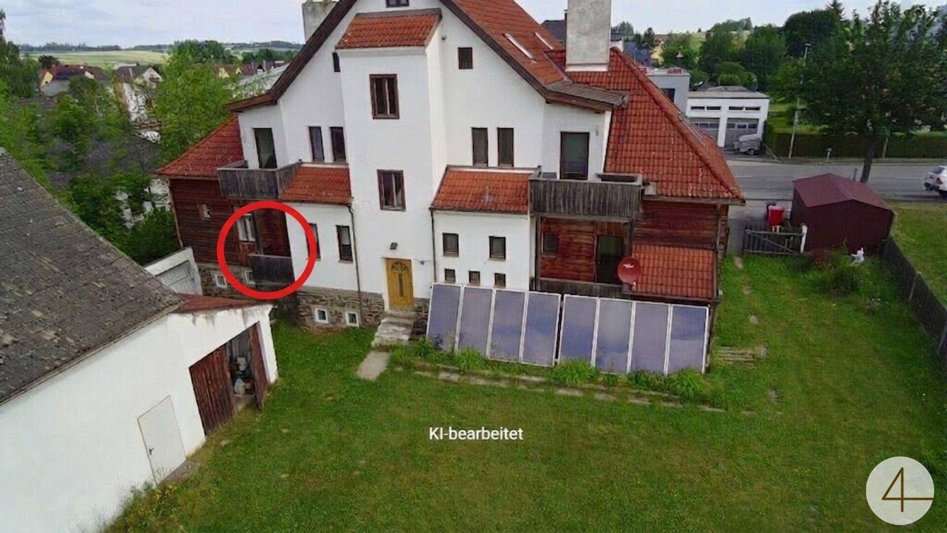 Rückansicht eines Altbaus mit Balkonen, Solaranlage auf dem Dach und einem weitläufigen Gartenbereich.