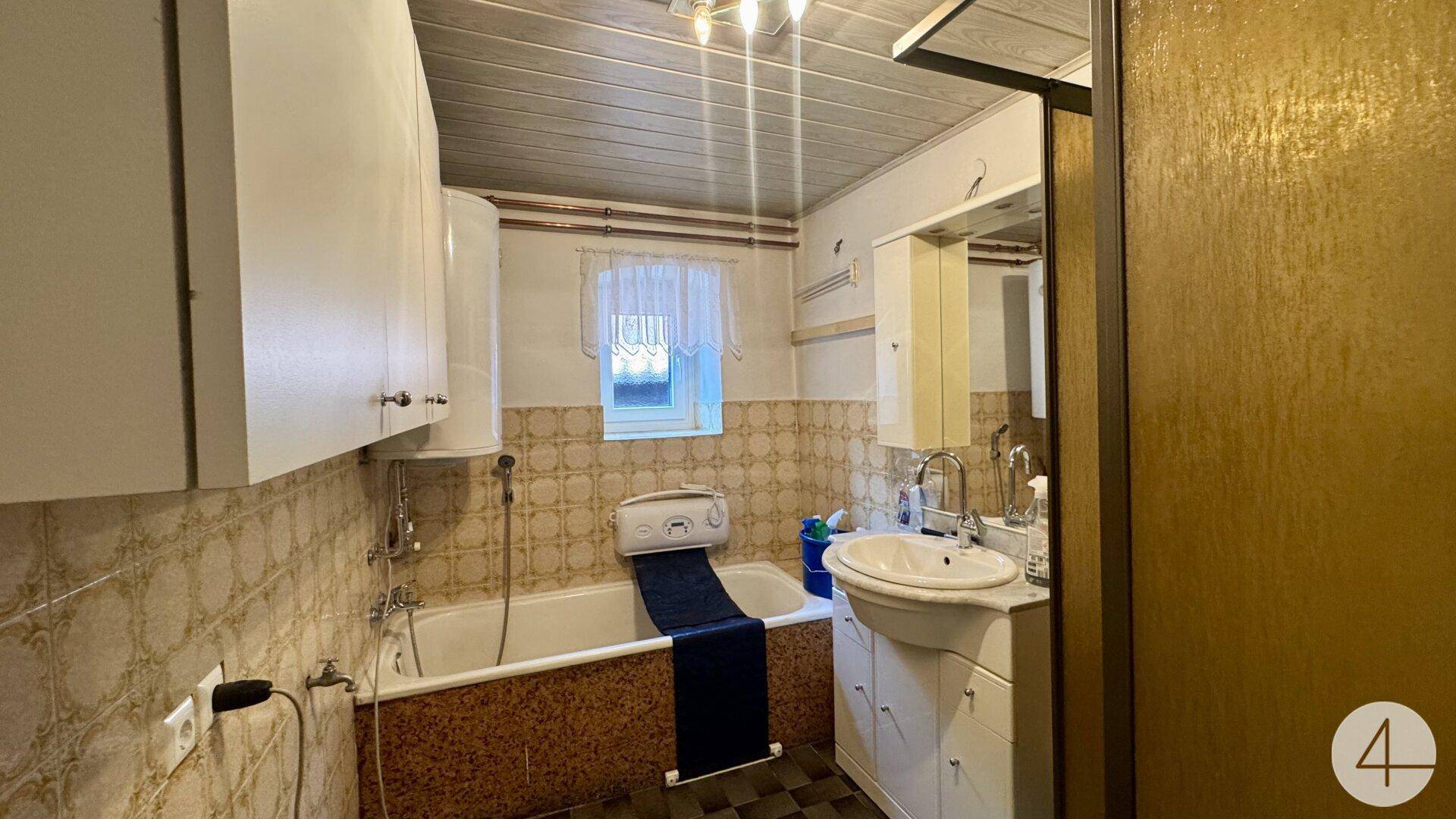 Badezimmer mit Badewanne, Waschbecken und gemusterten Fliesen im traditionellen Stil.