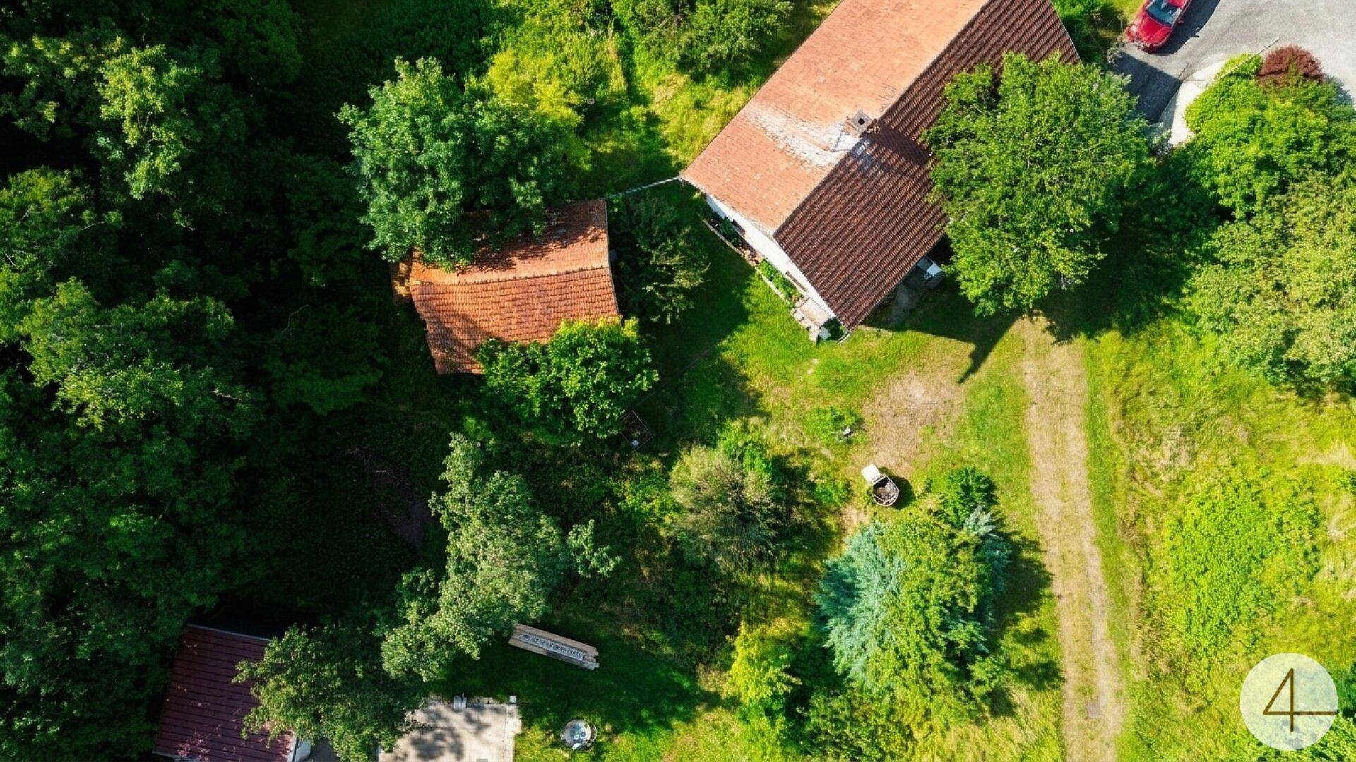 Vogelperspektive des Anwesens mit Haupthaus und Nebengebäude, eingebettet in eine grüne Landschaft.