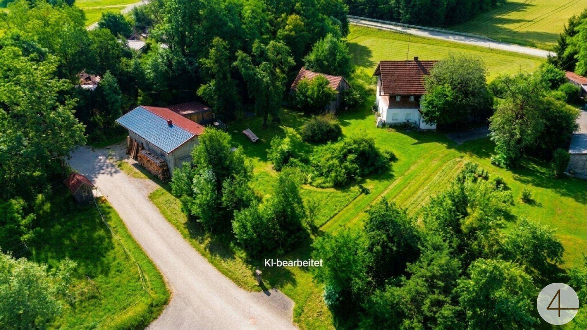 Luftaufnahme eines ländlichen Anwesens mit mehreren Gebäuden, umgeben von weiten Grünflächen und Bäumen.