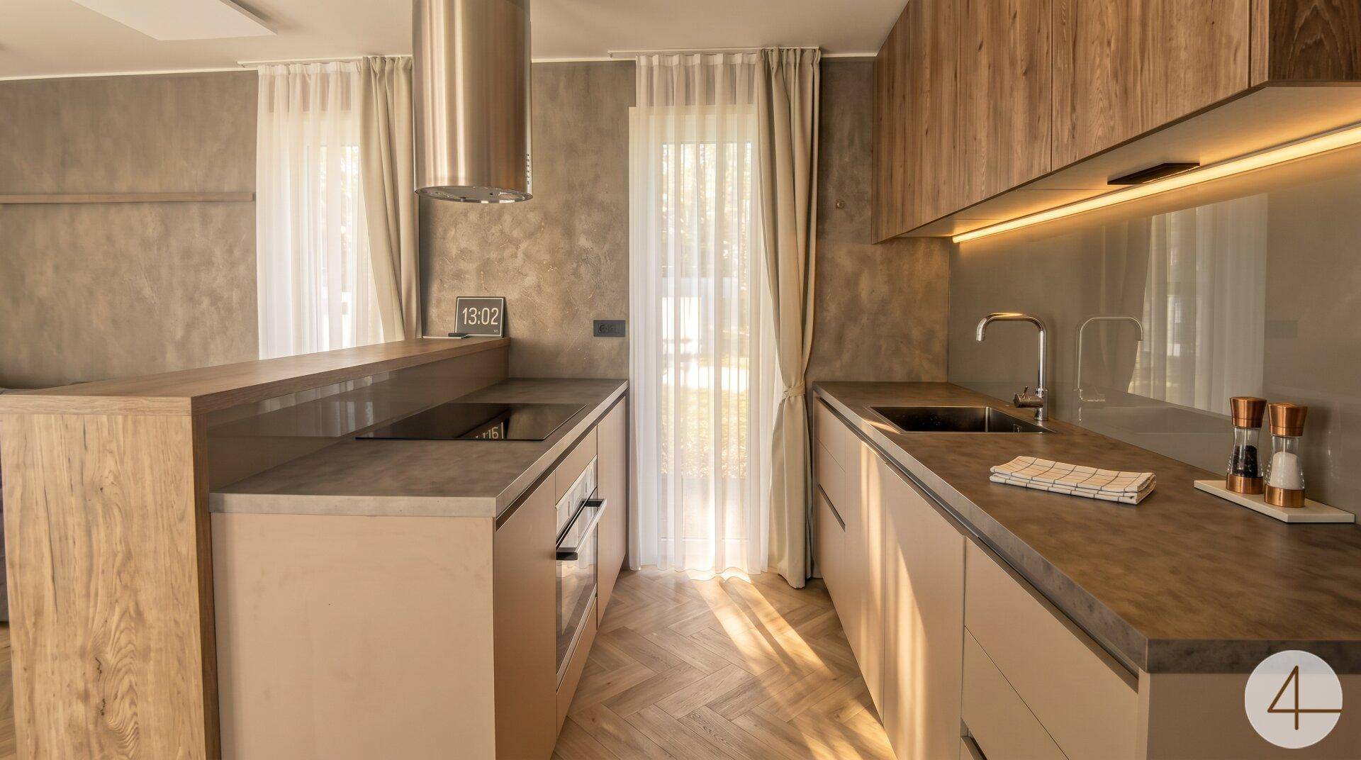 Moderne Küche mit Holzschränken, hellen Arbeitsplatten und Dunstabzugshaube aus Edelstahl.