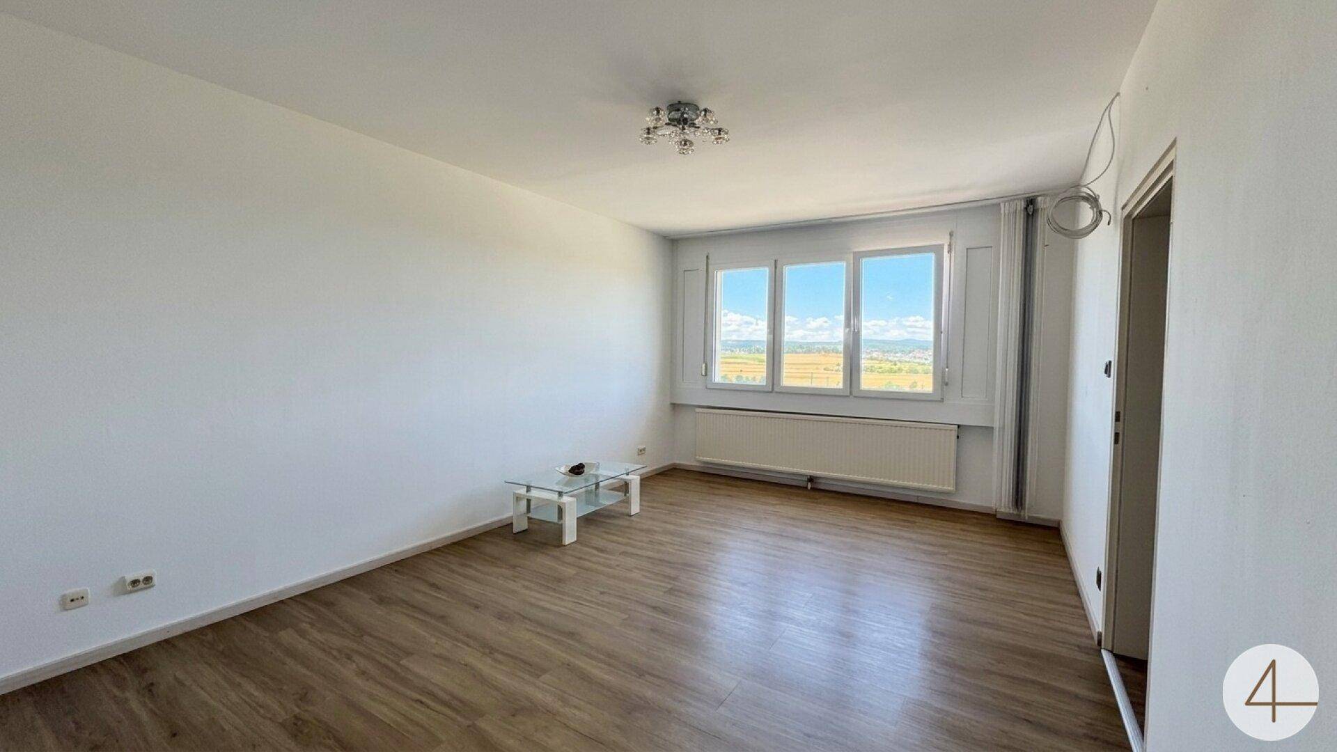 Geräumiges Wohnzimmer mit Laminatboden, großen Fenstern und weitem Ausblick.