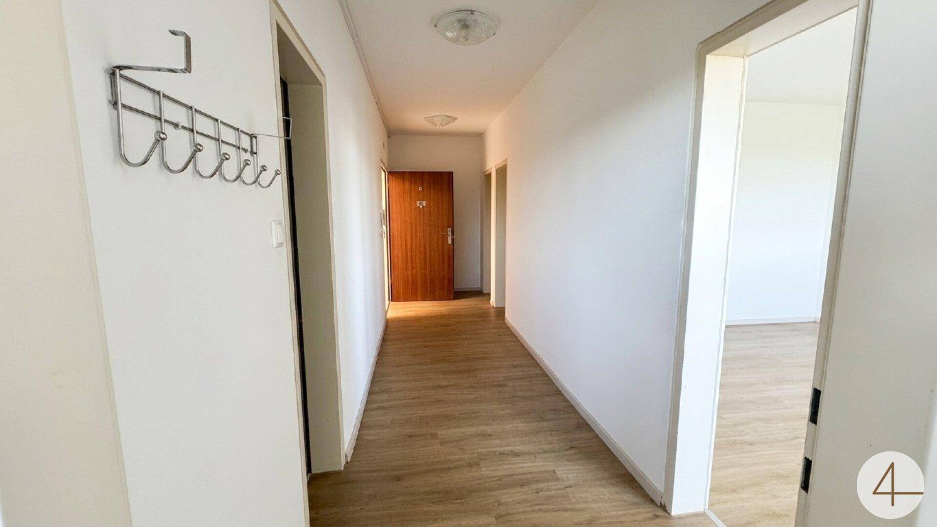 Heller Flur mit Laminatboden und Garderobe, der zu den weiteren Räumen führt.