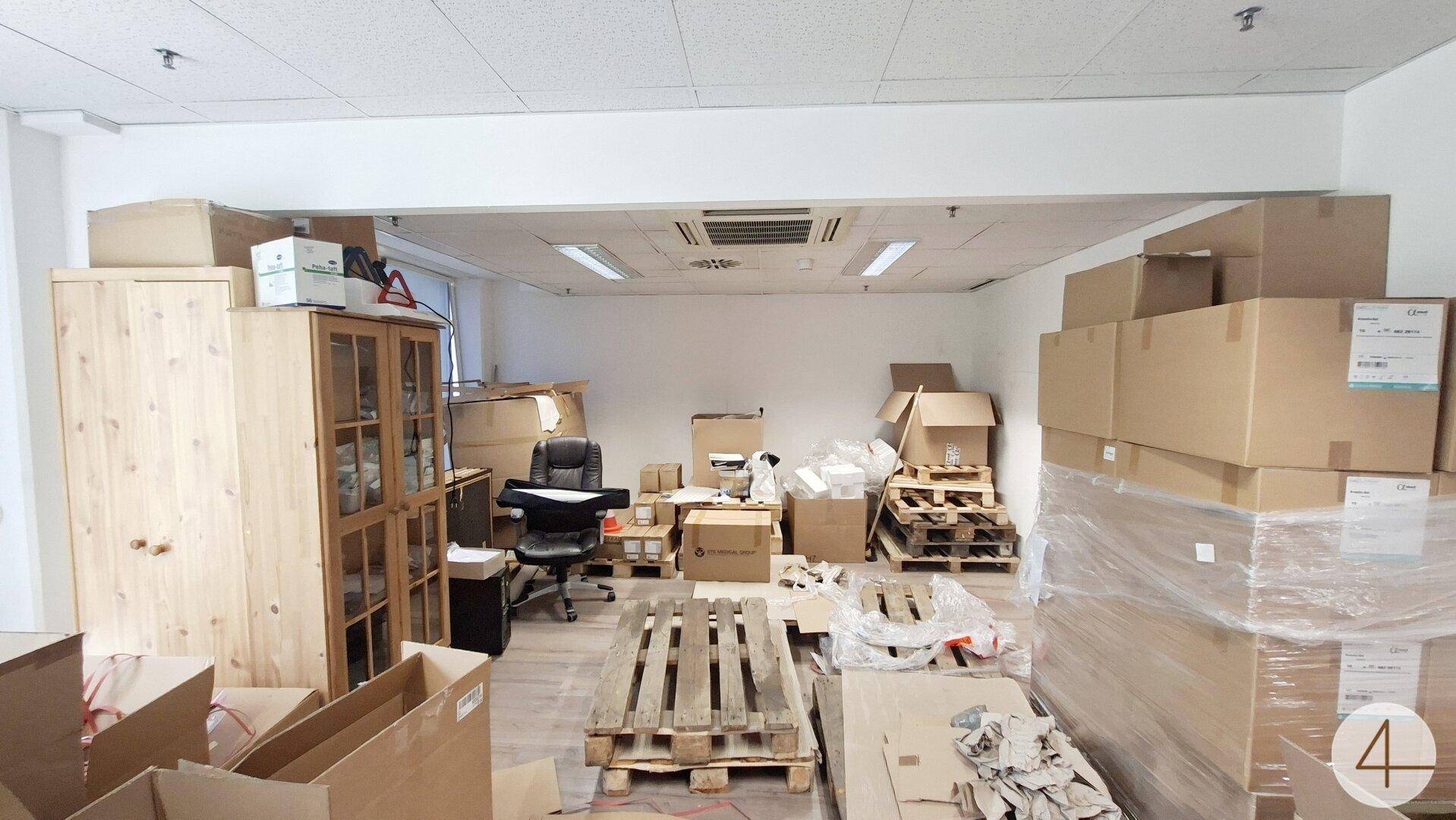 Lagerhalle mit zahlreichen Kartons, Holzpaletten und einem großen Holzschrank, bereit für den Versand.