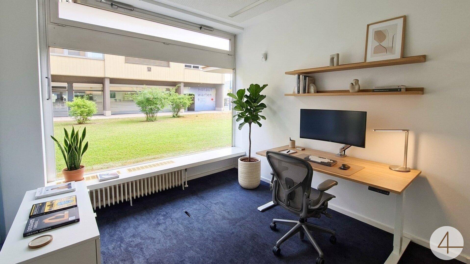 Modern eingerichtetes Büro mit Schreibtisch, ergonomischem Stuhl und Blick auf den grünen Innenhof.