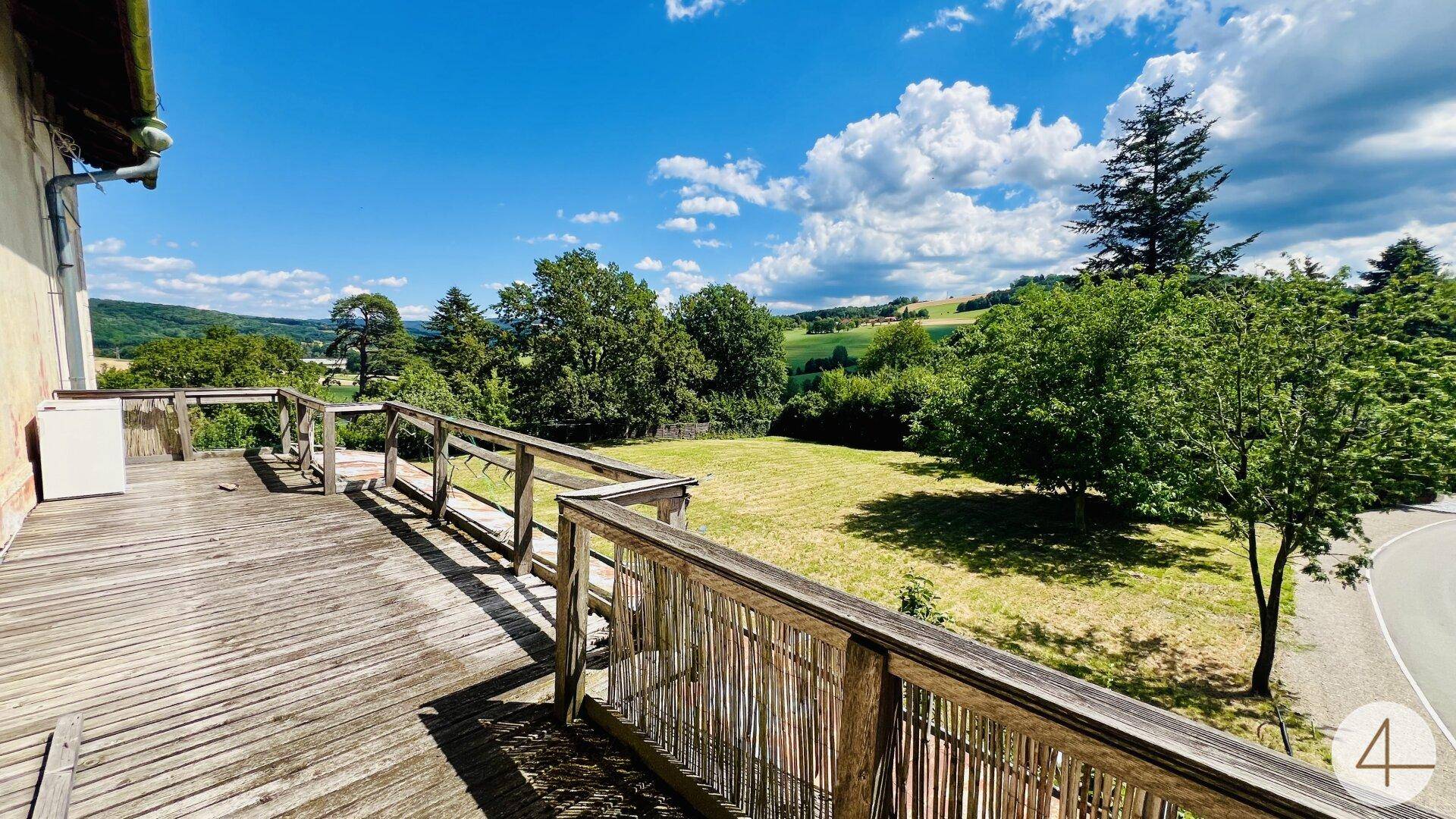 Große Holzterrasse mit Geländer bietet einen weiten Blick über die grüne Hügellandschaft.