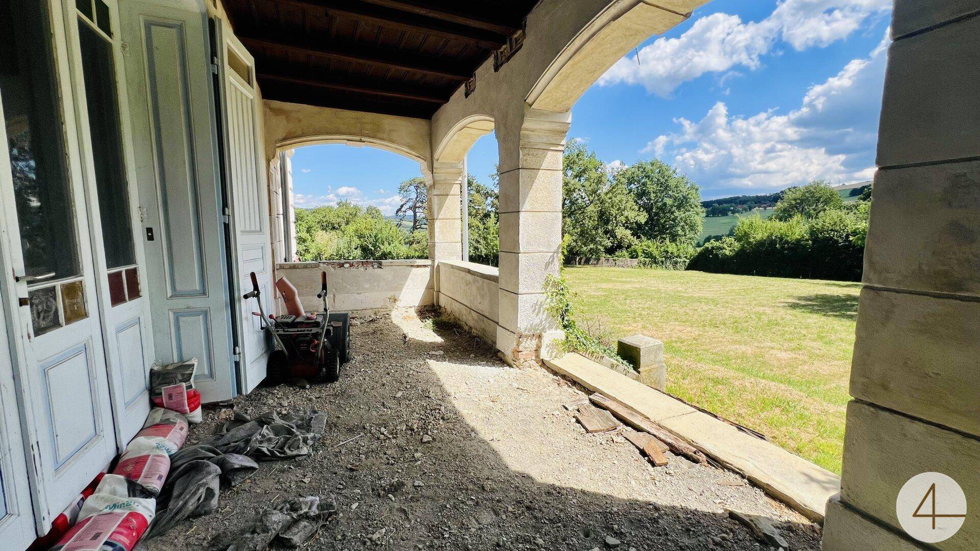 Überdachte Loggia mit Bögen und Blick ins Grüne, derzeit in einem renovierungsbedürftigen Zustand.