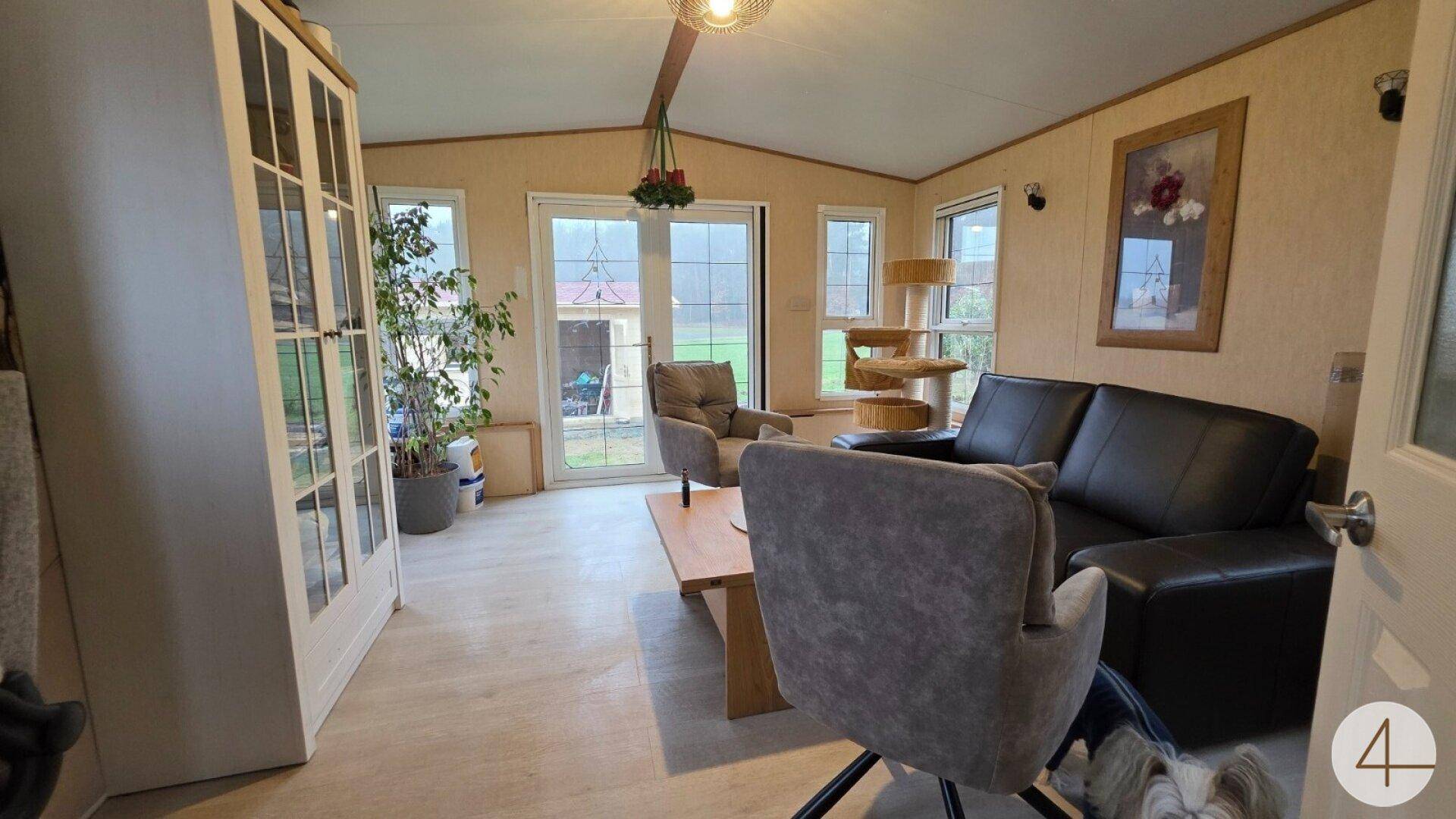 Helles Wohnzimmer mit Laminatboden, bequemen Sitzgelegenheiten und Zugang zur Terrasse.