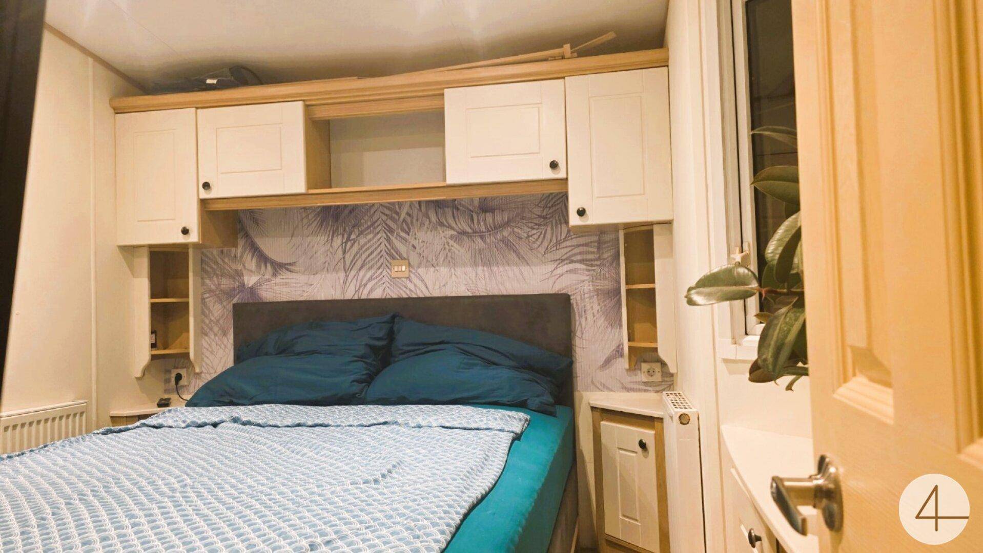 Schlafzimmer mit Doppelbett, praktischen Einbauschränken über dem Bett und Fenster.