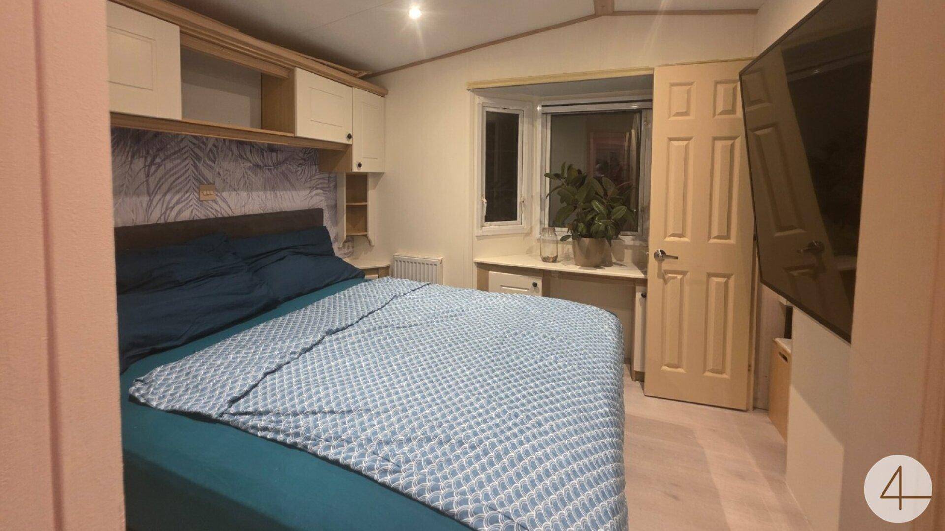 Gemütliches Schlafzimmer mit Einbauschränken, großem Bett und einem an der Wand montierten Fernseher.