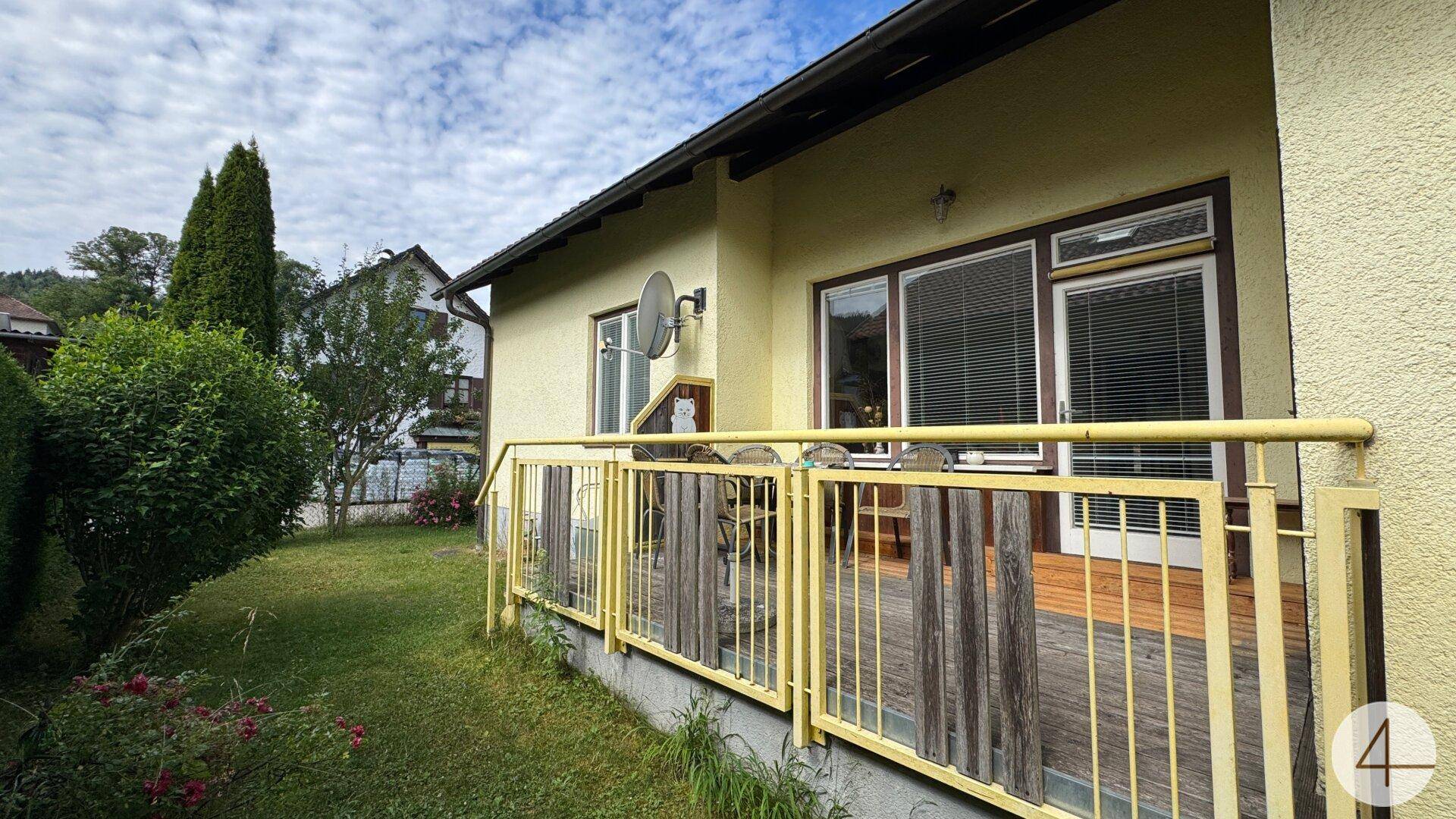 Holzterrasse mit gelbem Geländer und Blick auf den Garten, ideal für entspannte Stunden im Freien.