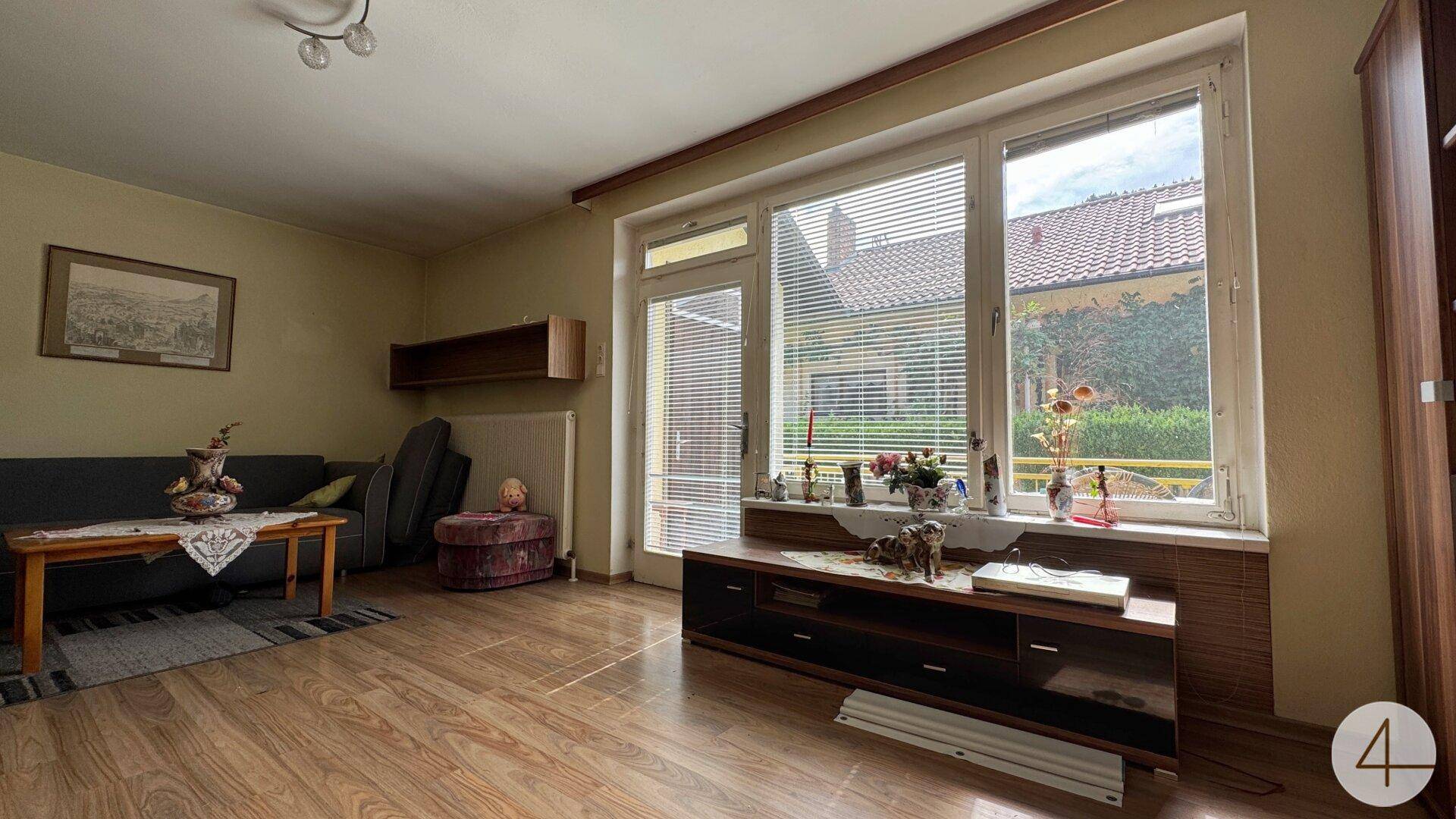 Geräumiges Wohnzimmer mit Laminatboden und viel Tageslicht durch die großen Fenster.