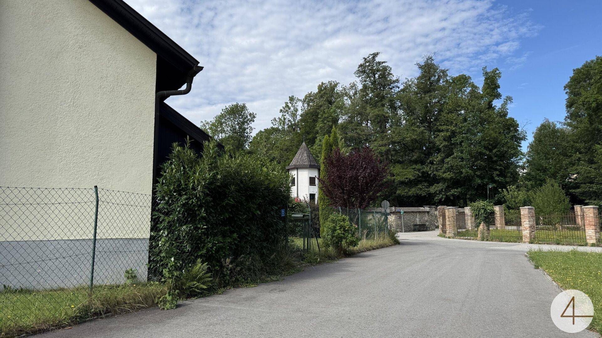 Ruhige Straße neben dem Grundstück mit Bäumen und einem Blick auf die umliegende Landschaft.