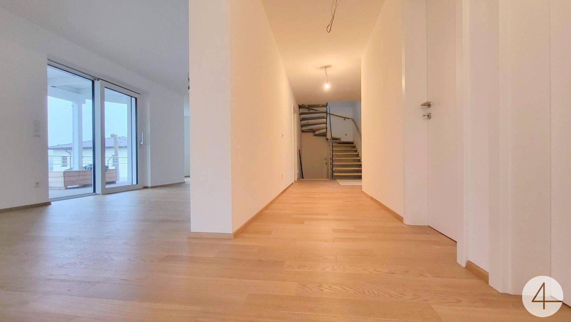 Heller Flur mit Holzparkett, Wendeltreppe und Zugang zu einer großen Terrasse.