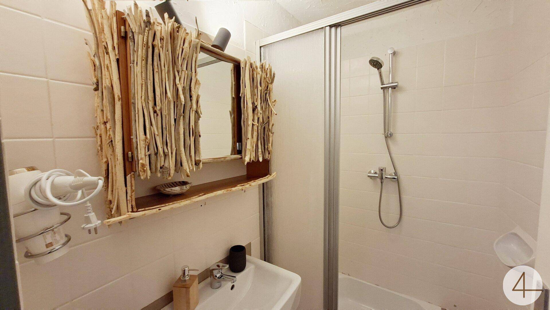 Kleines Badezimmer mit Dusche, Waschbecken und rustikalem Spiegelrahmen.