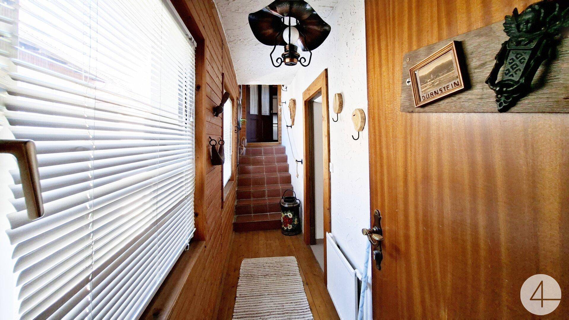 Rustikaler Flur mit Holzvertäfelung, Treppe und traditioneller Dekoration.