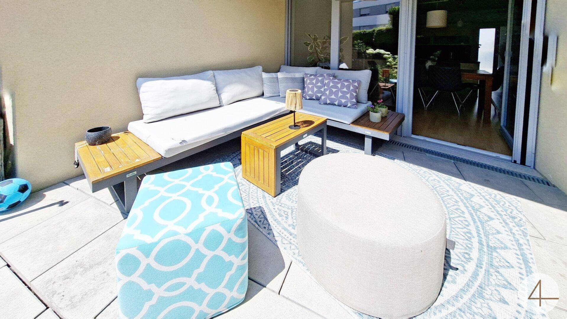 Detailansicht der Terrasse mit modernen Outdoor-Möbeln und Teppich.