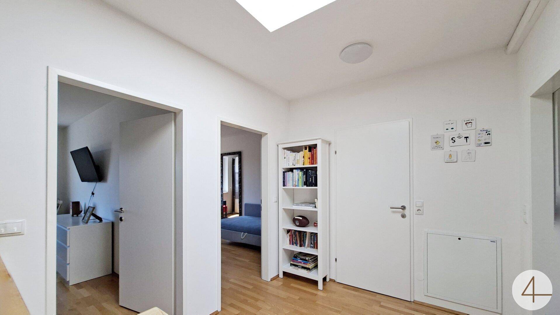 Heller Flur im Obergeschoss mit Holzboden und Bücherregal.